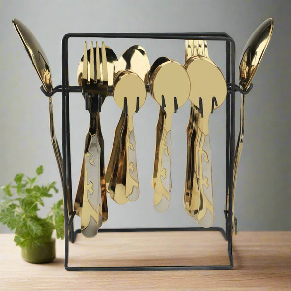 Gold cutlery set on a black stand with a plant in the background